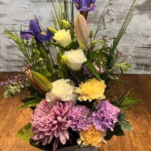 A tall box arrangement including fresh seasonal flowers; lilies, carnations and lissianthus.