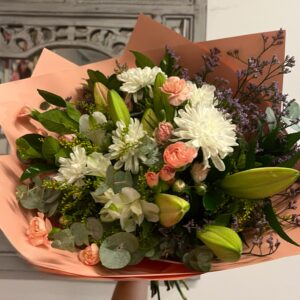 A bouquet of pink and white fresh flowers; including lilies, spray carnations, chrysanthemums, alstroemeria with greenery and flowering fill.