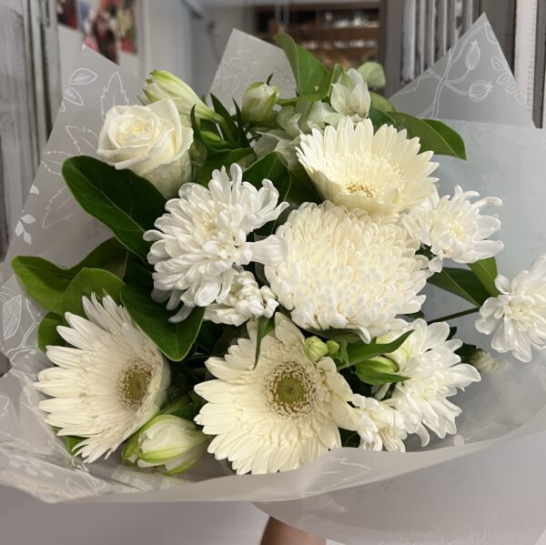 A lush bouquet in seasonal white flowers including gerberas, roses, disbud chrysanthemums and chrysanthemums.