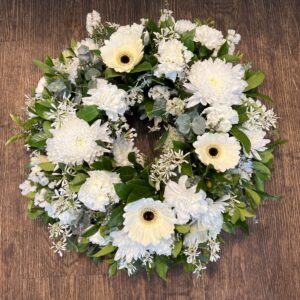 A beautiful lush wreath made with seasonal whites, including disbud chrysanthemums, gerberas, carnations and small filler flowers..