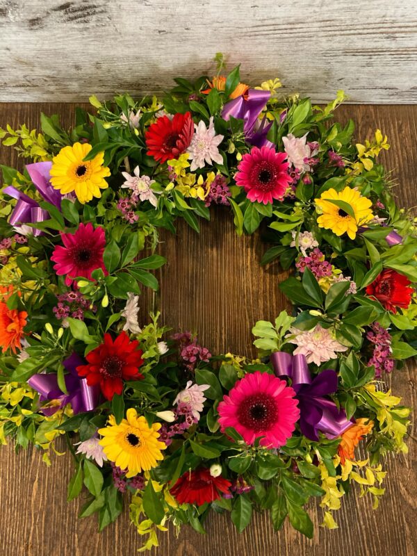 A wreath made with breath seasonal flowers including gerberas and chrysanthemums.