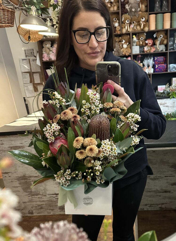 Florist at Westridge Florist Toowoomba holding native flower arrangement in store